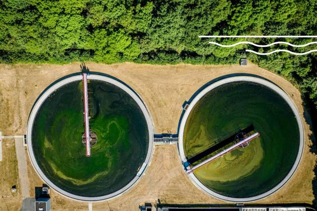 Aerial view of two circular wastewater treatment clarifiers with green water and rotating arms at a water treatment plant