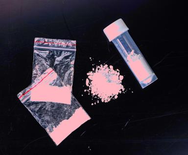 Image showing light pink powdered substance in small transparent plastic bags and a vial on a dark surface, illustrating substances in a controlled or recreational context. Ideal for articles about drug awareness, synthetic substances, or medical toxicology insights