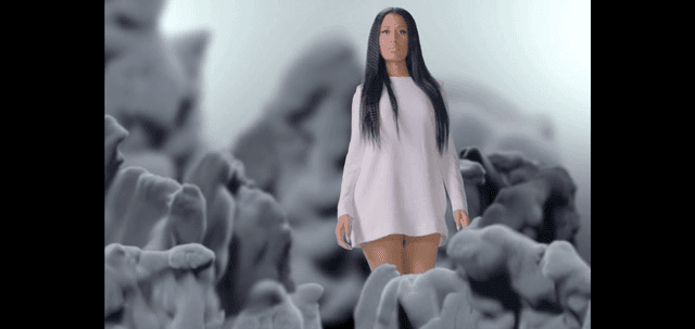 Still from “Pills n Potions” music video showing a pop artist in a white long-sleeve dress walking through gray abstract forms; theme of healing and forgiveness.